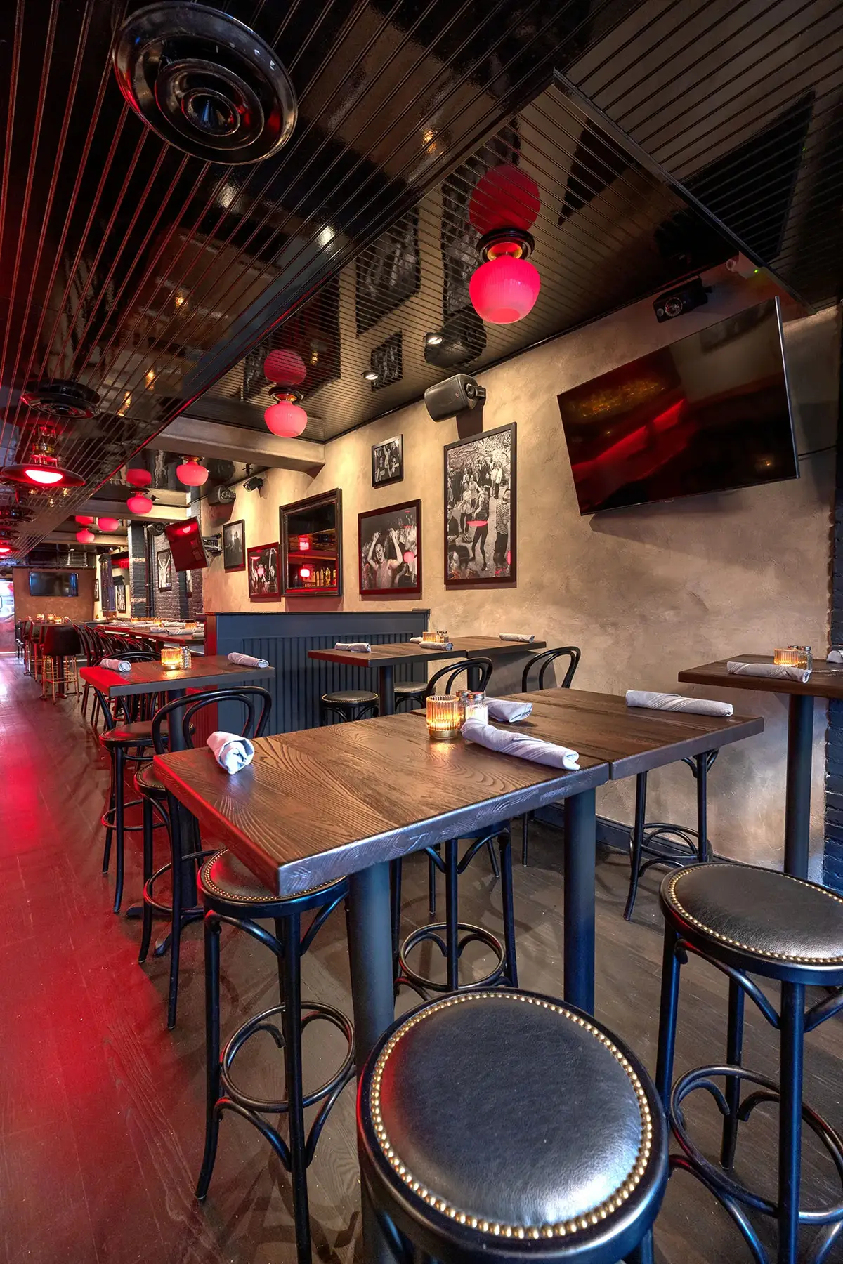 Sports bar with high-top tables, stools, and red pendant lighting.
