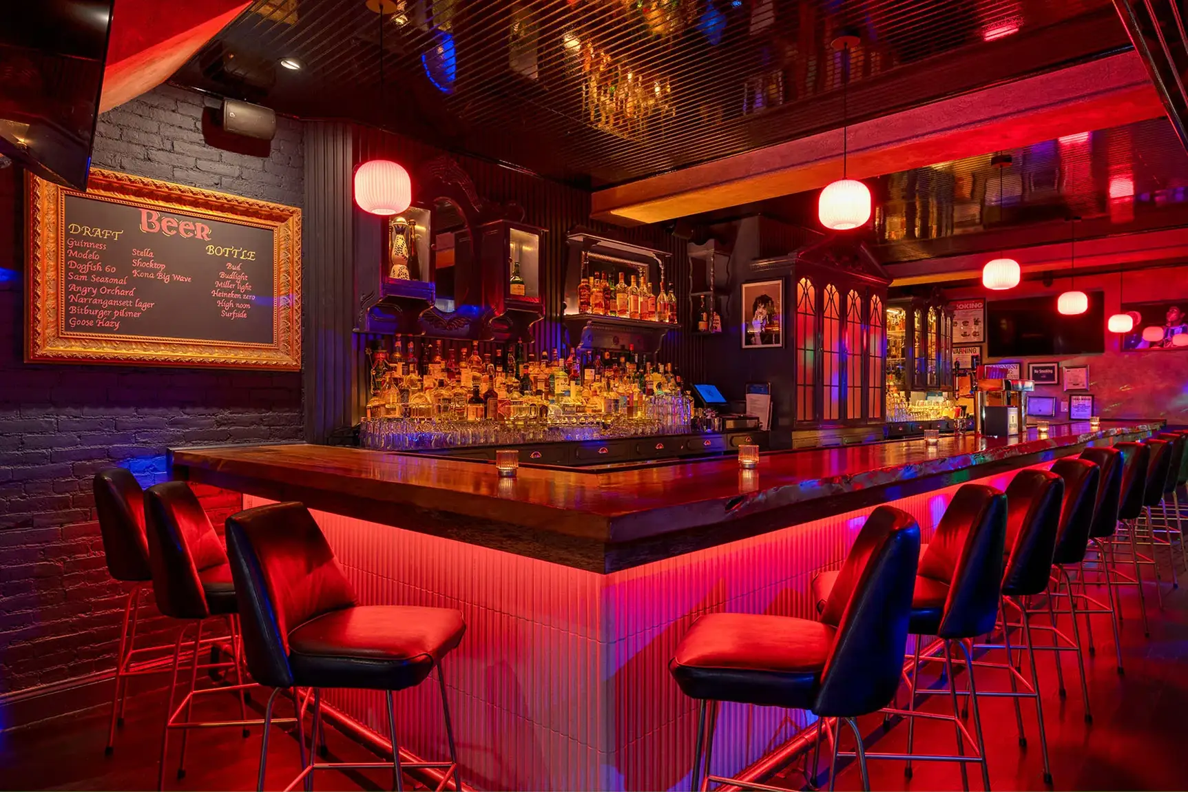 Modern bar with glowing red lights, stocked shelves, and black bar stools.