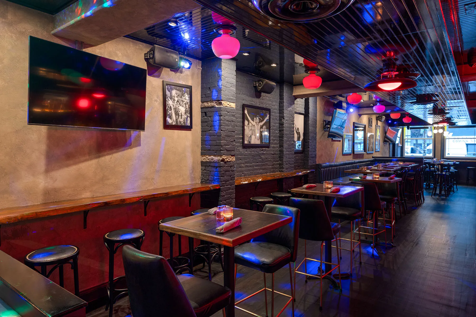 Contemporary bar with TVs, high-top seating, and red and blue accent lights.

