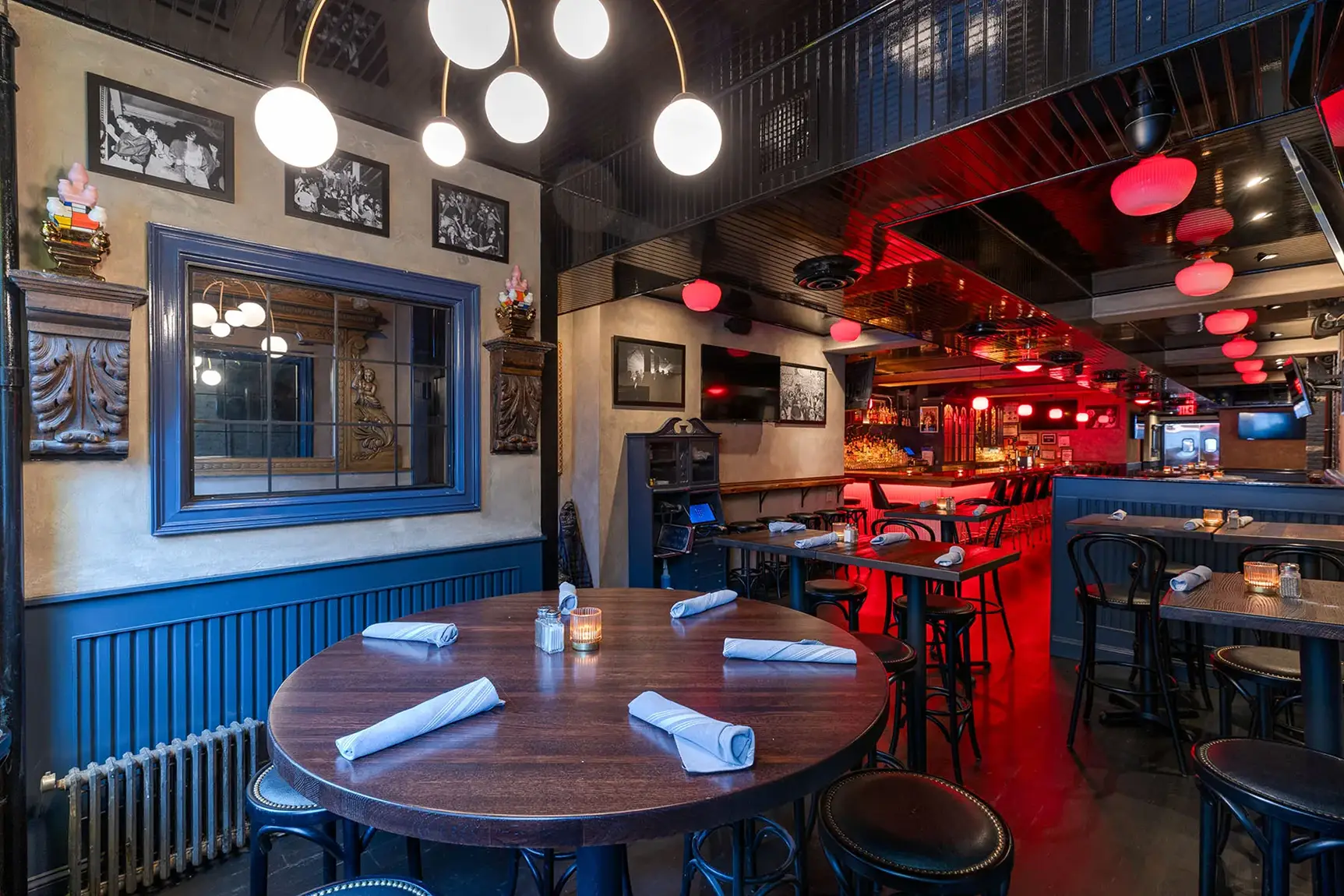 Cozy restaurant dining room with round tables and a view of the bar.
