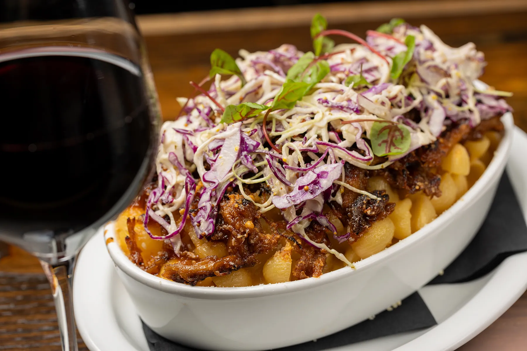 Pulled pork mac and cheese topped with fresh coleslaw and served with red wine.
