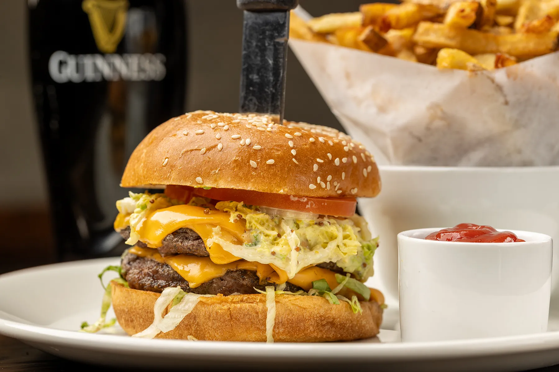 Double cheeseburger with lettuce, tomato, and melted cheddar on a sesame bun, served with fries and ketchup.